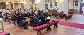 Zdjęcie wykonane wewnątrz kościoła. Widok skierowany jest od strony ołtarza na wnętrze. Widać ławki, wiernych. W pierwszych rzędach strażacy w galowych mundurach.