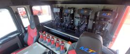 Zdjęcie przedstawia wnętrze kabiny nowego ciężkiego samochodu ratowniczo - gaśniczego. Wewnątrz widać aparaty powietrzne, latarki. 