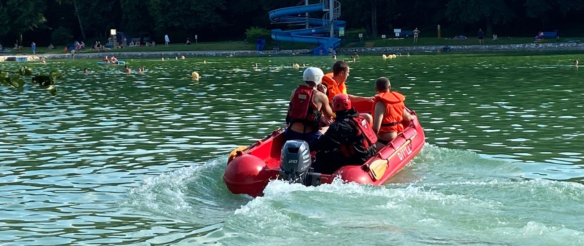 Strażacy pływają w łodzi.