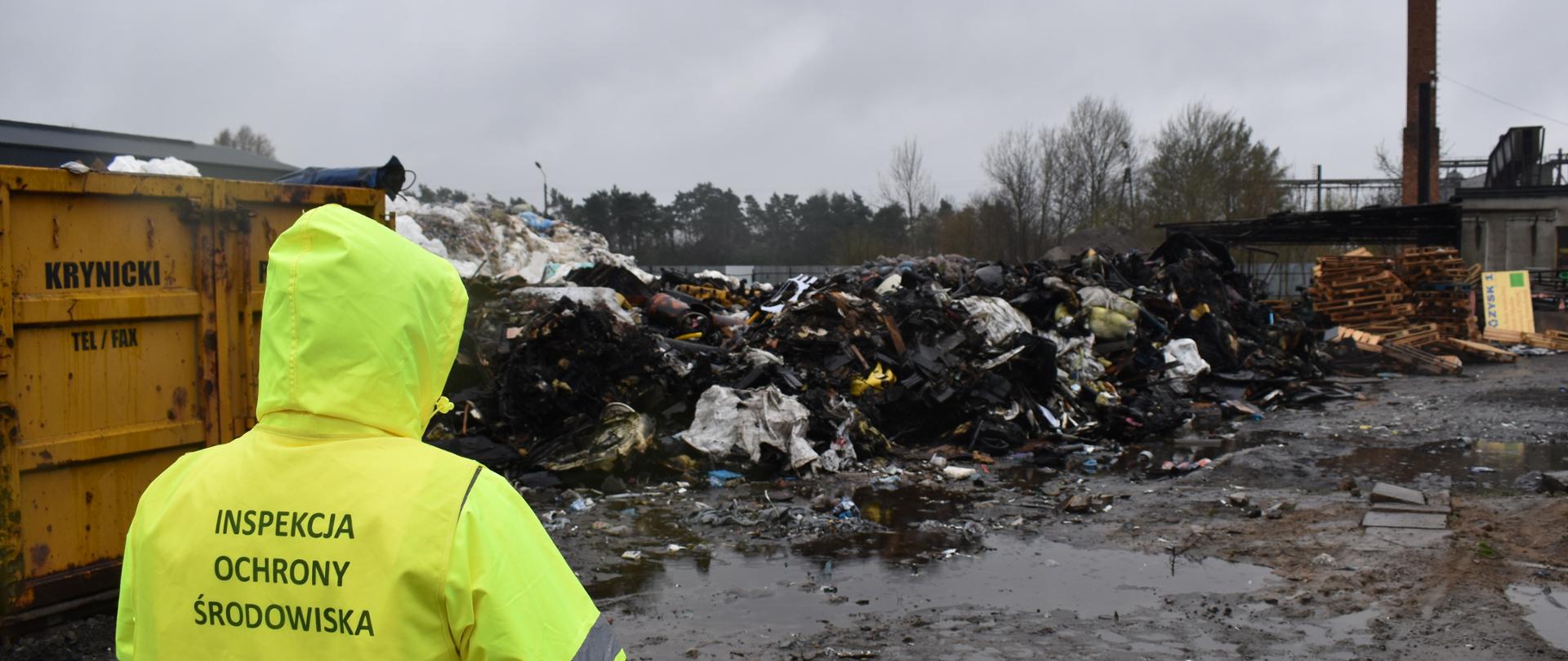 Inspektor Wojewódzkiego Inspektoratu Ochrony Środowiska prowadzi oględziny miejsca pożaru odpadów.