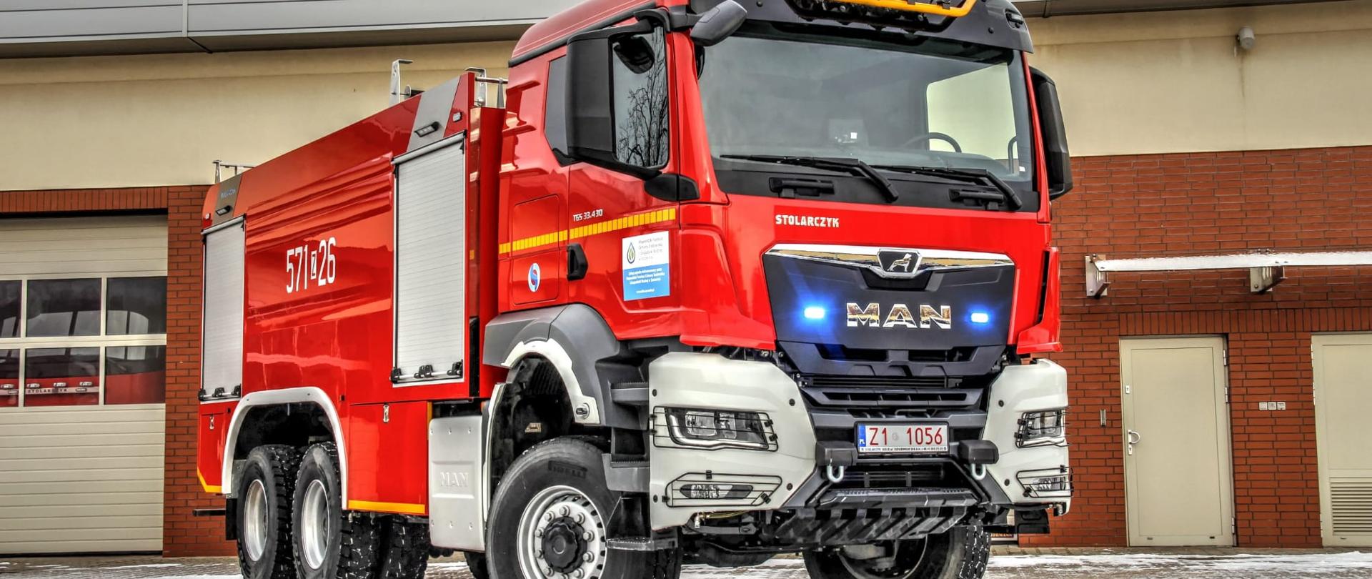 Zdjęcie z przedniej prawej strony ciężkiego samochodu ratowniczo-gaśniczego GCBA 9,5/60 6x6 na tle garaży KP PS w Wałczu