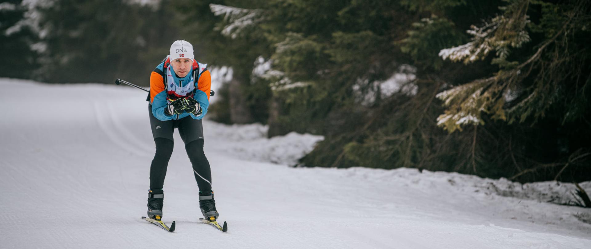 Zdjęcie przedstawia uczestnika Biegu Piastów zjeżdżającego z góry na nartach biegowych.
