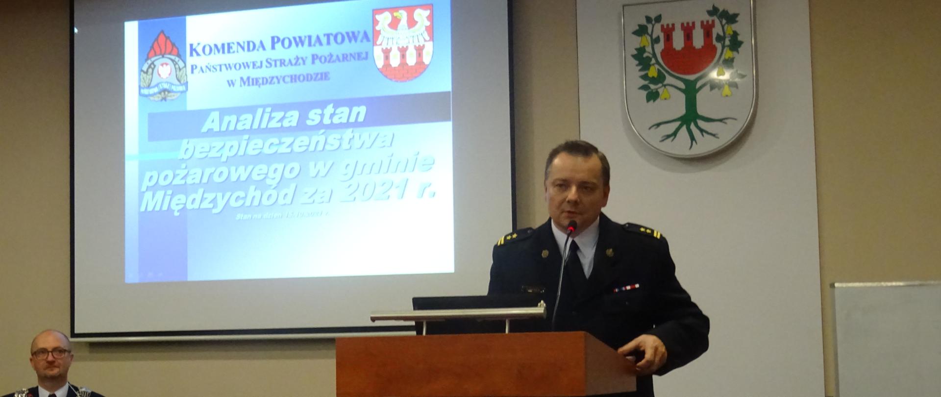 Zdjęcie przedstawia Zastępcę Komendanta Powiatowego PSP w Międzychodzie, który prezentuje stan ochrony przeciwpożarowej w mównicy.