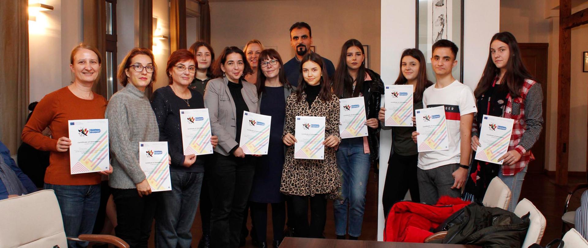 Na zdjęciu 13 osób trzymających w dłoniach dyplomy. Osoby są uczestnikami programu Erasmus+.