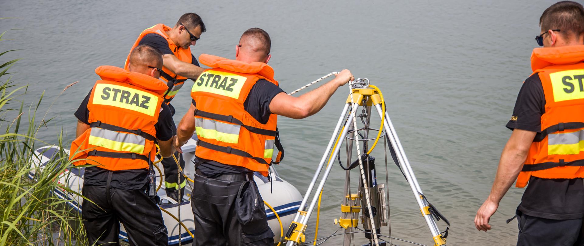 Na zdjęciu widocznych czterech strażaków ze Specjalistycznej Grupy Sonarowej "Nysa" wykonujących działania ratownicze na akwenie wodnym.