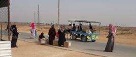 kobiety które czekają na drodze i trzymają pozyskane paczki z pomocą humanitarną