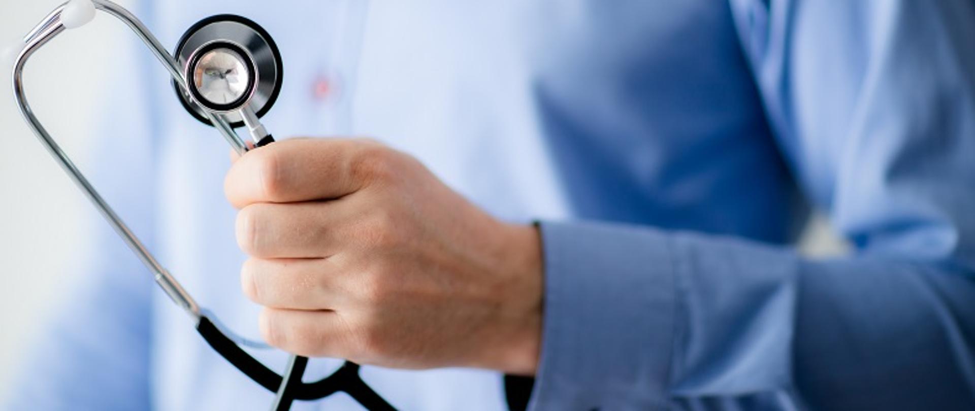 Dłoń mężczyzny w niebieskiej koszuli ze stetoskopem