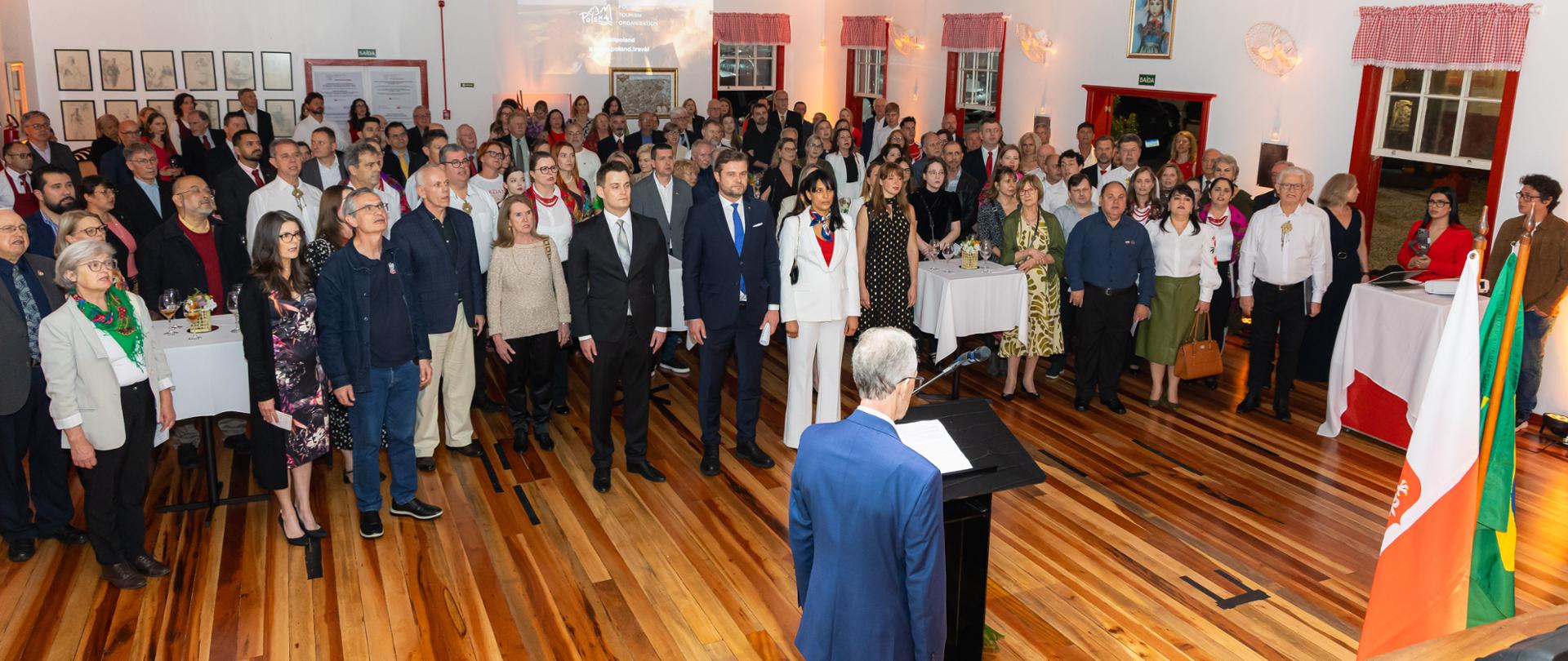 Licznie zgromadzona publiczność w czasie uroczystości w siedzibie Tow. im. J. Piłsudskiego, śpiewająca hymn w pozycji na baczność