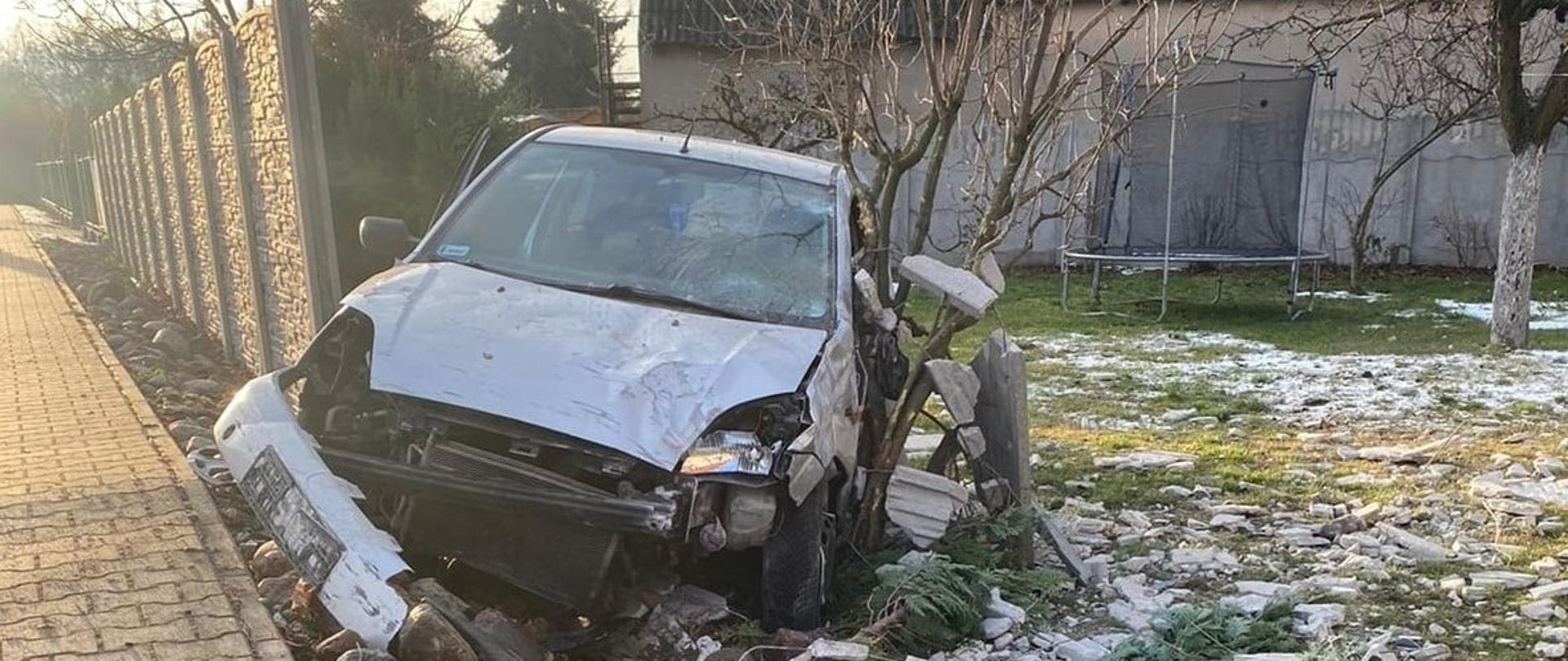 Rozbite auto w wyniku wypadku drogowego, uszkodzone ogrodzenie