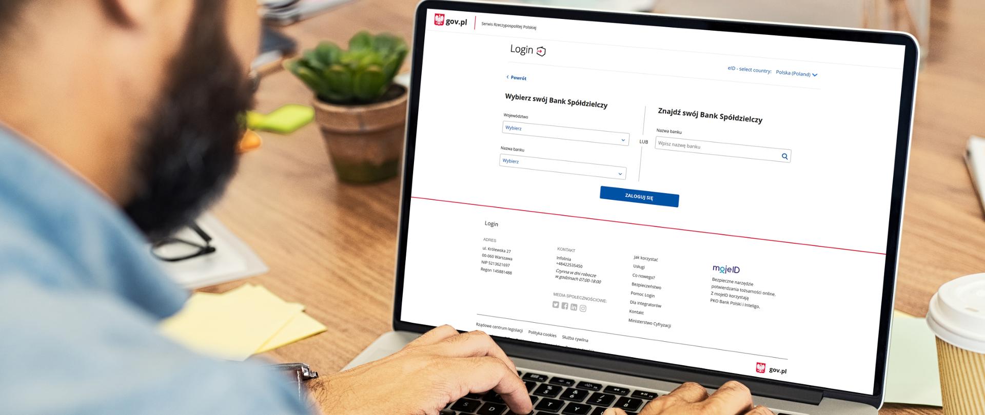 Mężczyzna siedzący przed laptopem. Na ekranie komputera - ekran logowania na gov.pl. Widoczne teksty "Wybierz swój bank spółdzielczy", "Znajdź swój bank spółdzielczy".