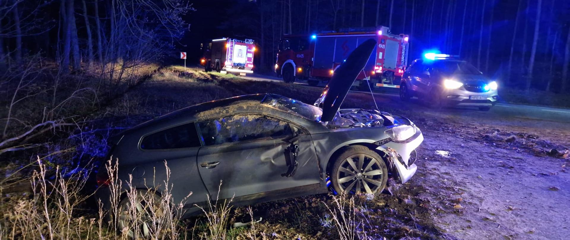 samochód na poboczu widziany z boku w tle samochody pożarnicze