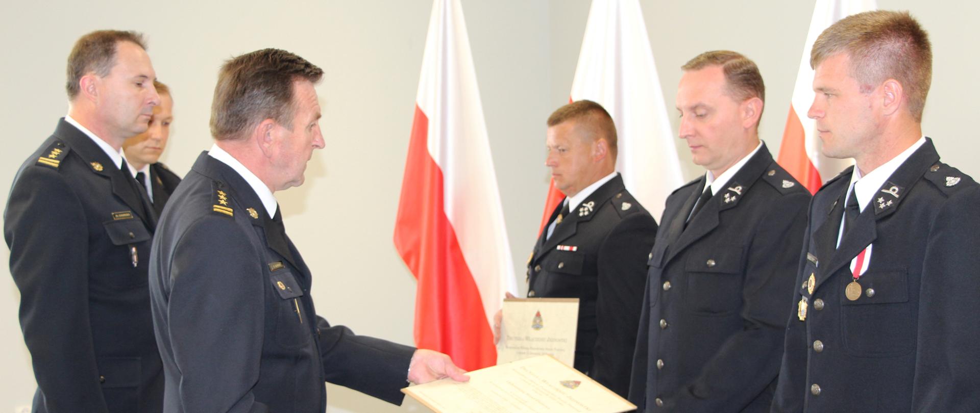 Zdjęcie przedstawia Komendanta Miejskiego w Kielcach wręczającego decyzje o włączeniu do KSRG przedstawicielom jednostek OSP