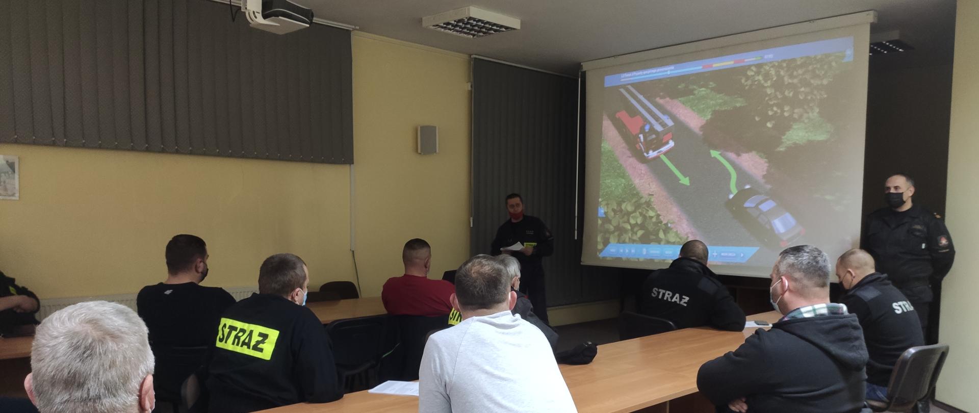 Instruktor jazdy z Ośrodka Szkolenia Kierowców w Skierniewicach przeprowadza szkolenie dla naczelników oraz kierowców OSP omawia kwestie zasad bhp eksploatacji pojazdów oraz przepisów bezpieczeństwa ruchu drogowego. Naczelnicy i kierowcy OSP uważnie słuchają prelekcji.