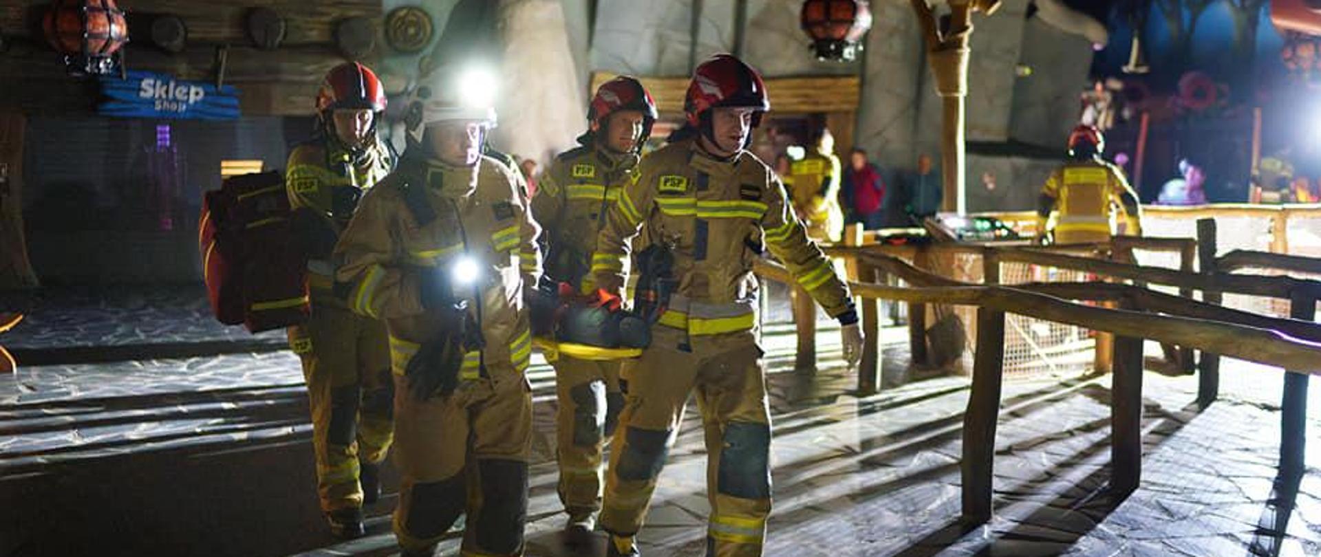 strażacy ewakuujący osobę nposzkodowaną na noszach