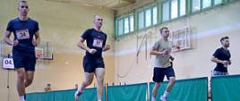 Czterech mężczyzn biegnących po wyznaczonych torach na sali gimnastycznej podczas konkurencji beep-test