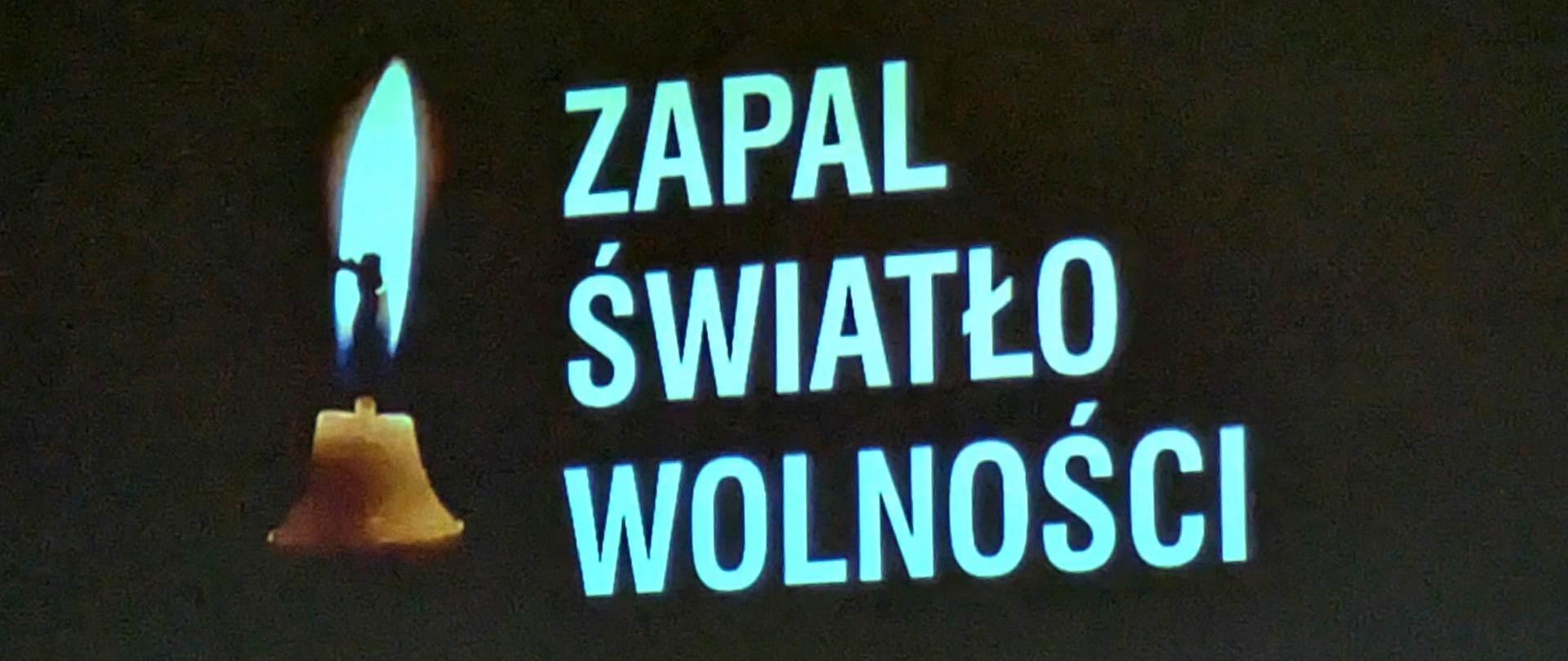 Fragment ekranu, na czarnym tle widać zapaloną świeczkę i biały tekst: ZAPAL ŚWIATŁO WOLNOŚCI, 13 grudnia, 19.30