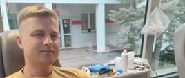 Strażak w umundurowaniu służbowym piaskowym podczas oddawania krwi 