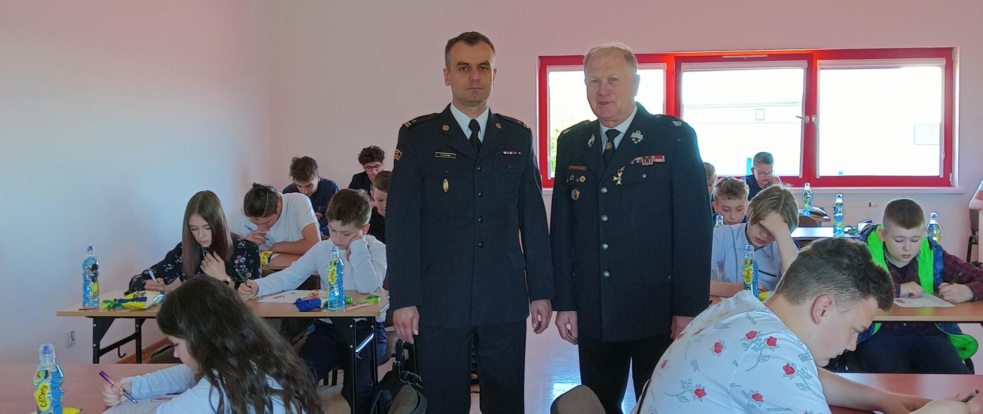 Uczestnicy OTWP piszą test, na drugim planie Z-ca Komendanta Powiatowego PSP w Ostrowcu Św. z Prezesem Powiatowego Związku OSP 