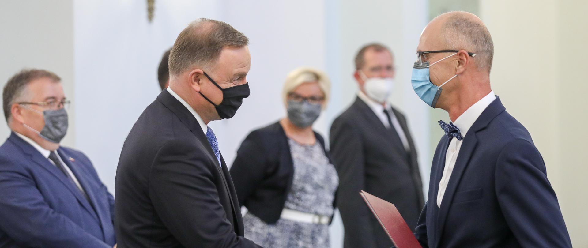 Prezydent ściska rękę jednego z profesorów.