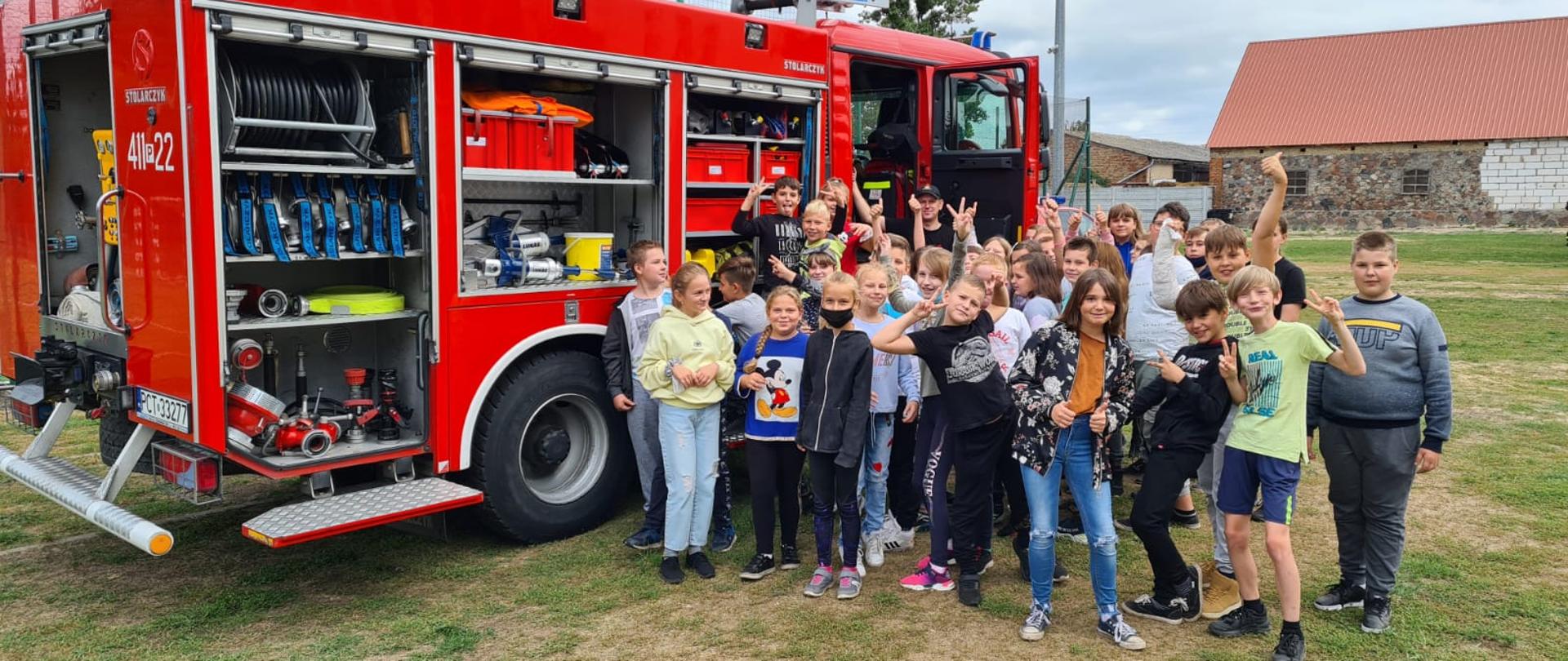 Zbiórka dzieci na tle wozu strażackiego.
