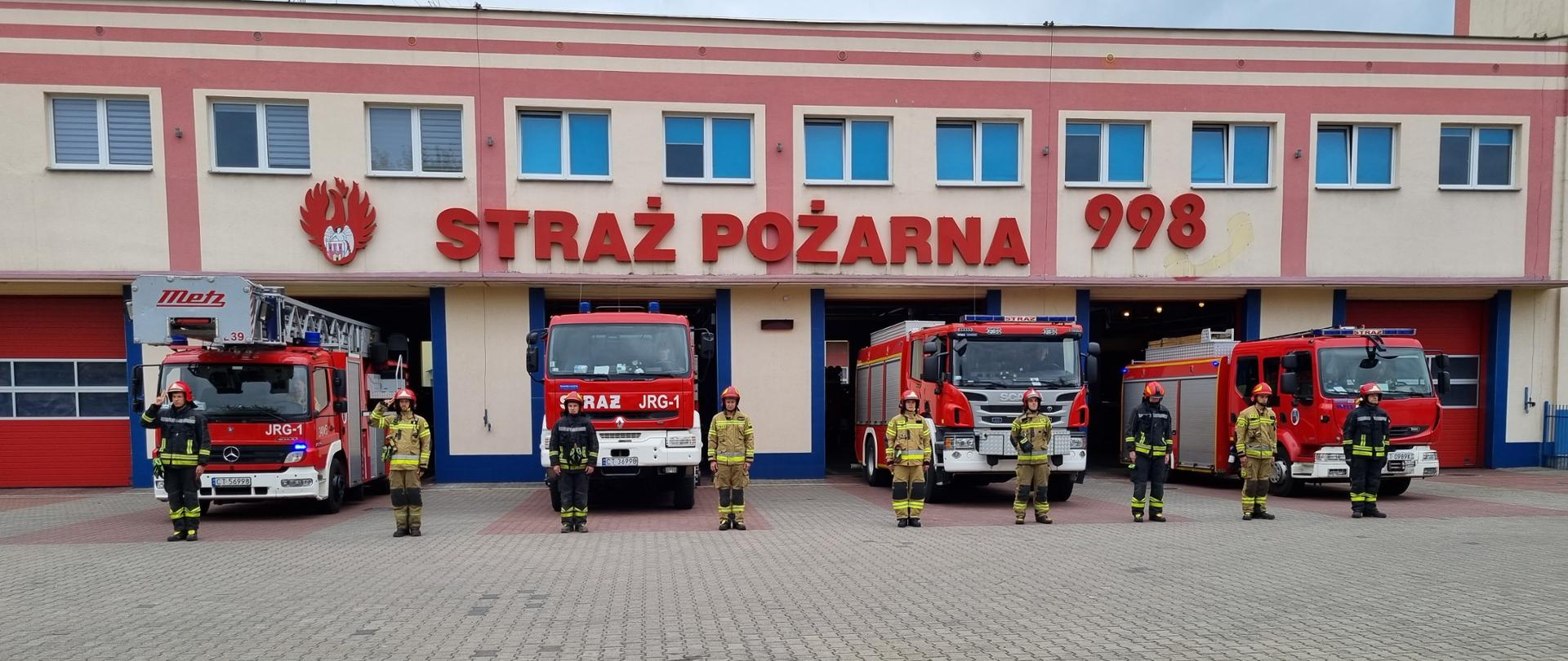 Strażacy JRG1 Państwowej Straży Pożarnej przyłączyły się tradycyjnie do ogólnopolskiej inicjatywy uczczenia rocznicy wybuchu Powstania Warszawskiego. Stoją na baczność przed pojazdami JRG1, które zostały wystawione przed garaż. Pojazdy mają włączone sygnały dźwiękowe i świetlne.