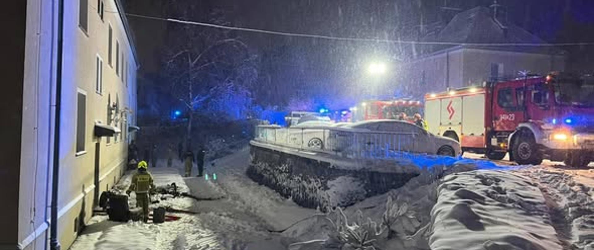 Na zdjęciu znajduję się pojazd strażacki oraz budynek mieszkalny