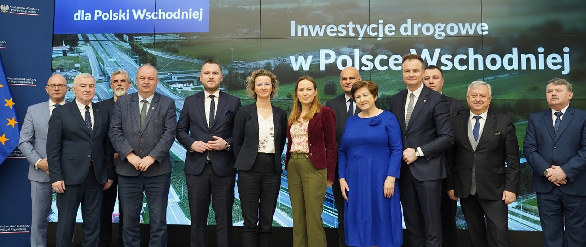 Minister funduszy i polityki regionalnej Katarzyna Pełczyńska-Nałęcz z marszałkami województw, którzy podpisali umowy na dofinansowanie rozwoju dróg w regionie, minister stoi na scenie w otoczeniu gości, po lewej od minister K. Pełczyńskiej-Nałęcz stoi p.o. prezes PARP Joanna Zębaczyńska-Świątek, następnie wiceminister funduszy i polityki regionalnej Konrad Wojnarowski
