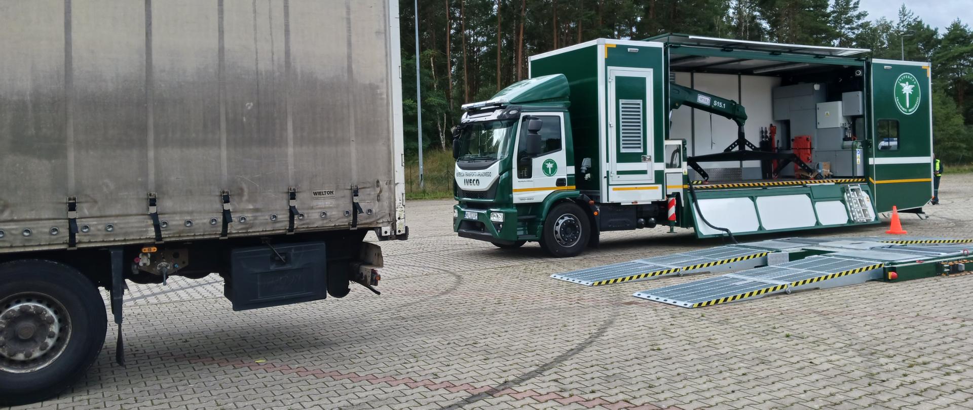 Od lewej: tył naczepy ciężarowej z niesprawnymi hamulcami przy dwóch kołach. Z tyłu kontrolowanego zestawu stoi rozłożona Mobilna Jednostka Diagnostyczna zachodniopomorskiej Inspekcji Transportu Drogowego.