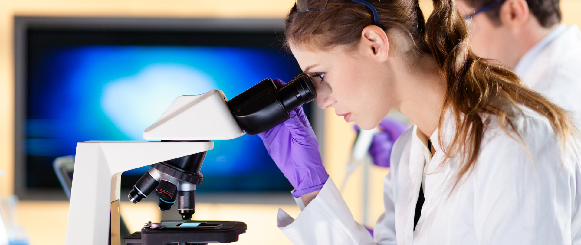 Kobieta w okularach patrząca przez mikroskop