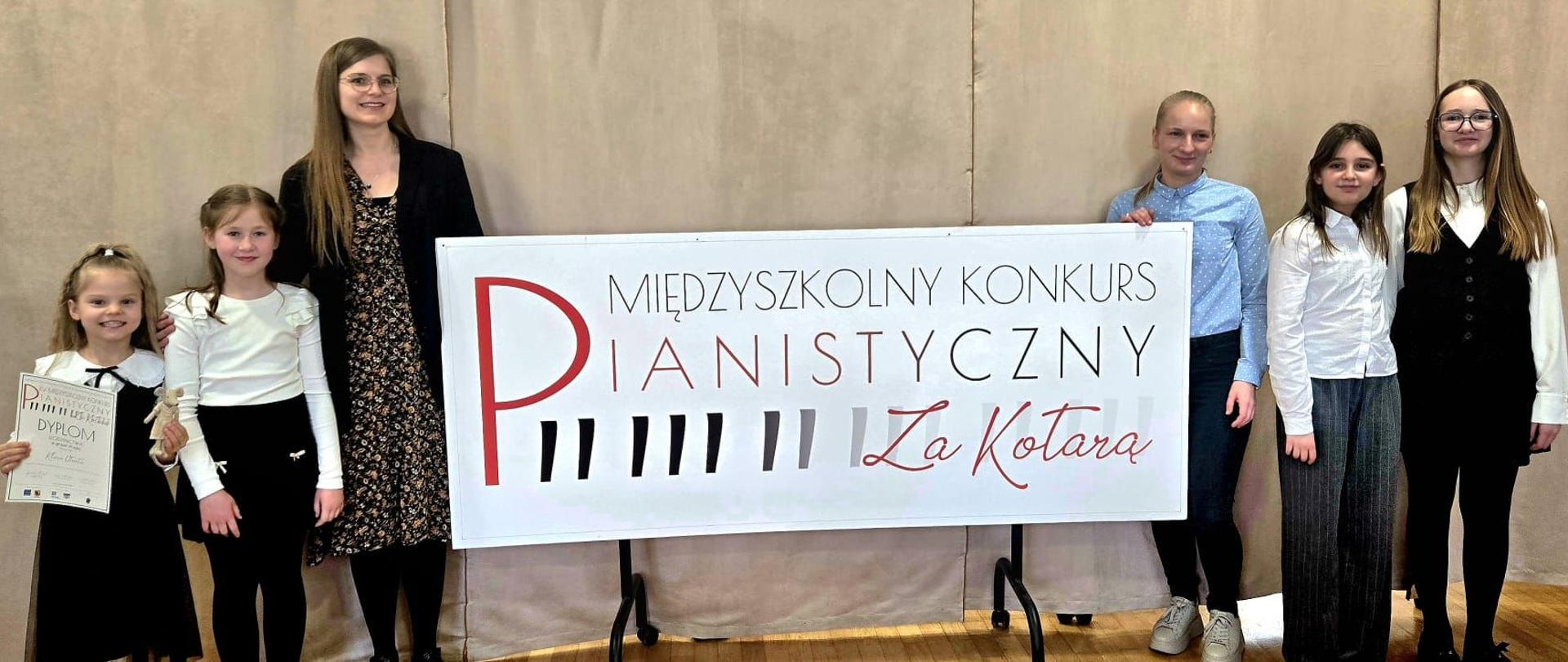 Uczennice naszej szkoły wraz ze swoimi nauczycielkami przy banerze "międzyszkolny konkurs pianistyczny Za kotarą"