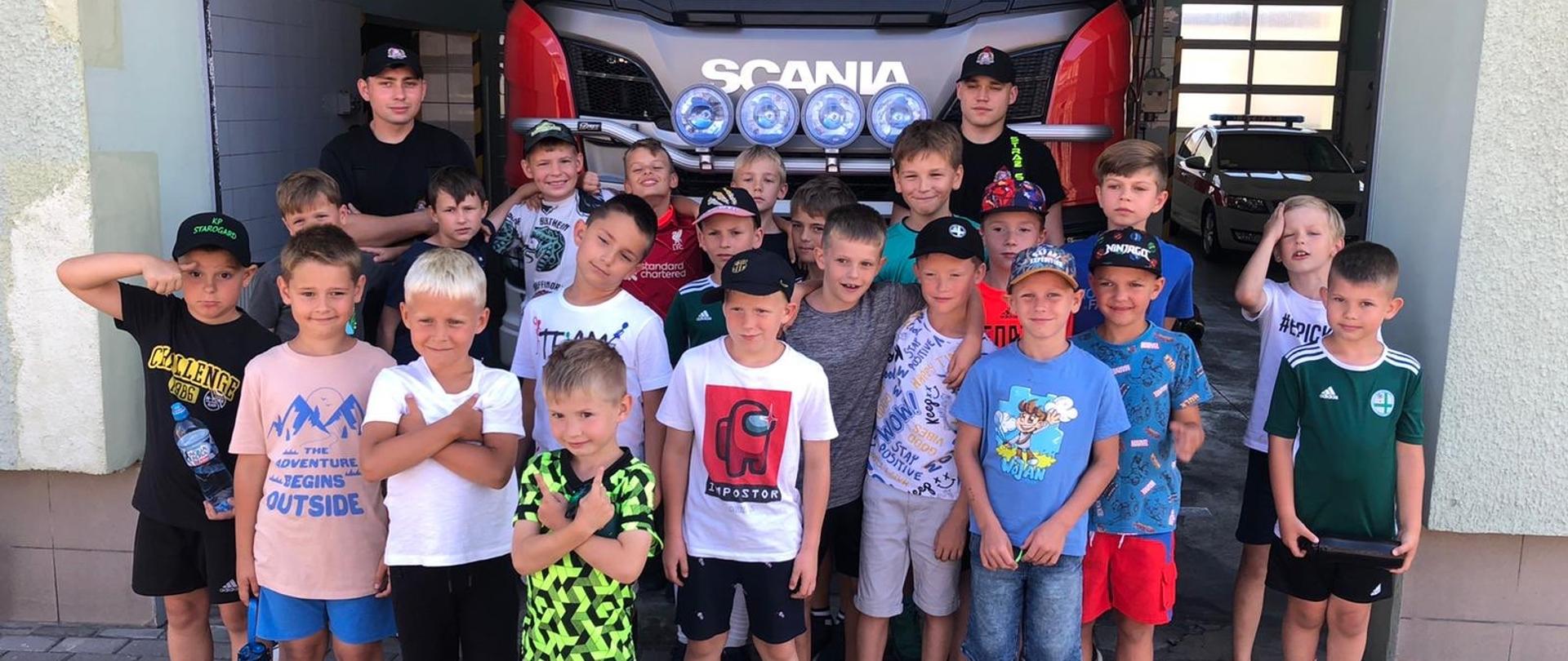 Zdjęcie przedstawia grupę dzieci na tle samochodu pożarniczego