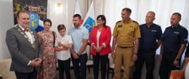 Chłopiec z rodzicami, Burmistrzem, Starostą, Strażakiem, Policjantami na zdjęciu grupowym