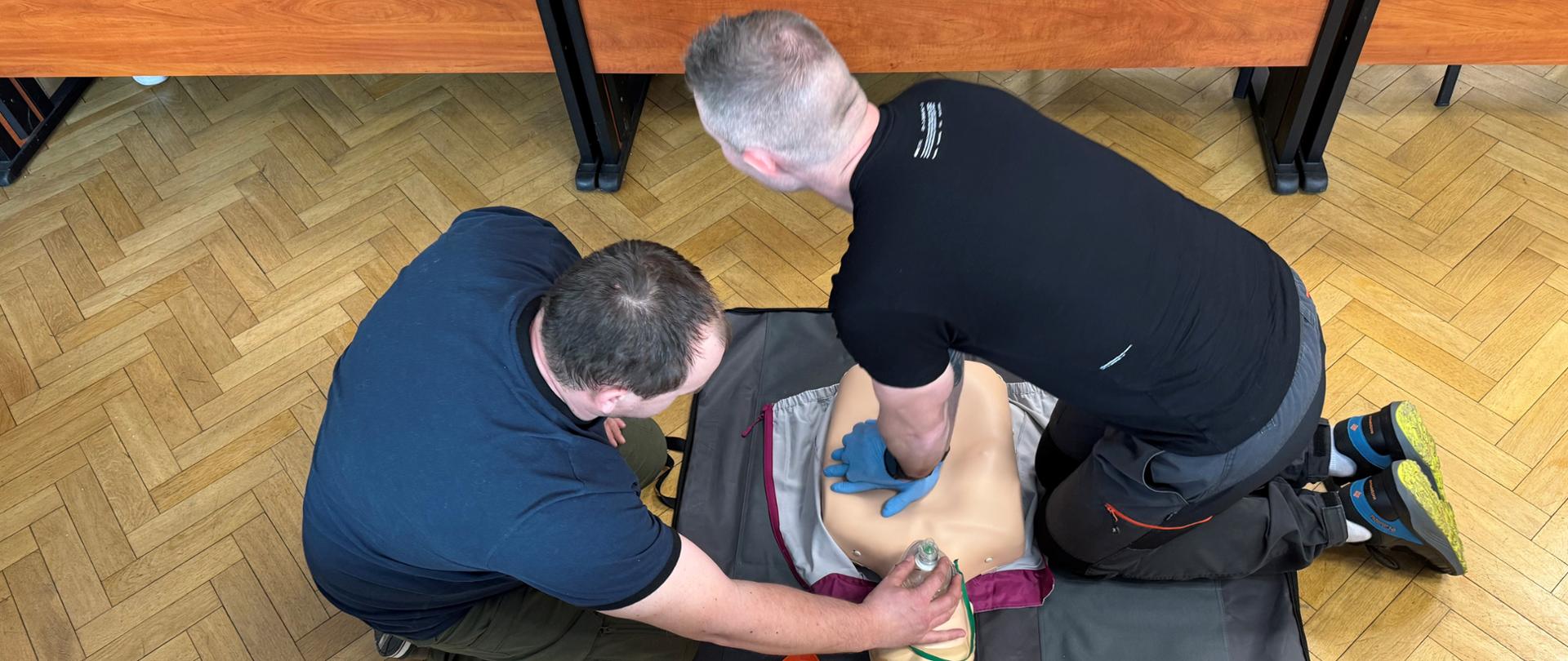 Pracownik WIOŚ w Warszawie szkoli się wraz z instruktorem z udzielania pierwszej pomocy. Wykorzystuje manekina, na którym można ćwiczyć resuscytacji krążeniowo-oddechowej.