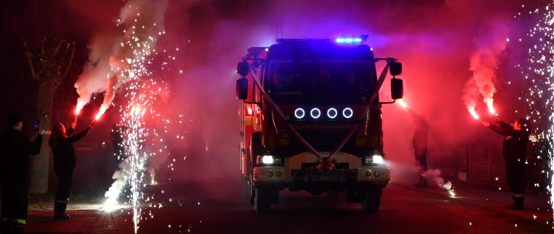 Nowy wóz pożarniczy w szpalerze fajerwerków.