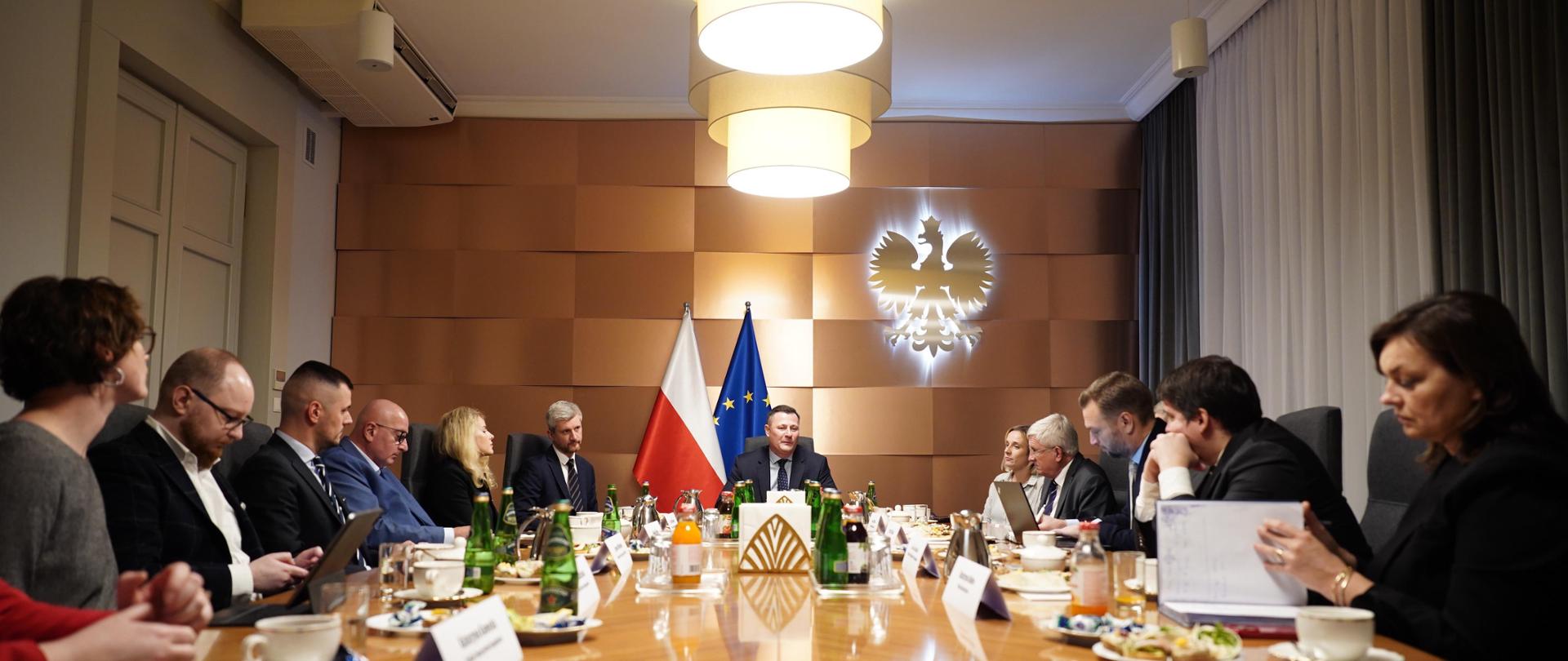 Kilkanaście osób siedzi przy stole 