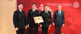 trzech funkcjonariuszy oraz starosta na tle ścianki w reku wyróżnienie