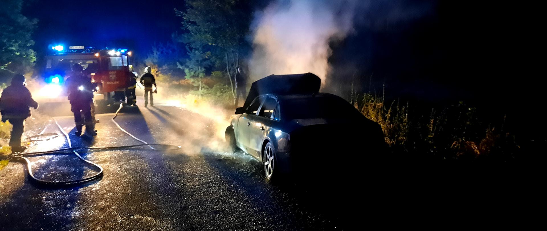 Na zdjęciu palący się samochód osobowy oraz strażacy podczas działań