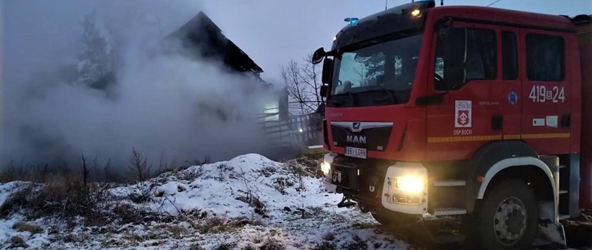 Na zdjęciu widać wóz ratowniczo-gaśniczy w tle paląca się drewniana stodoła