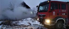 Na zdjęciu widać wóz ratowniczo-gaśniczy w tle paląca się drewniana stodoła