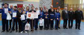 Zdjęcie zbiorowe – zwycięzcy zawodów – OSP Przytkowice z pucharami i medalami w otoczeniu gości i obserwatorów. 