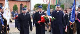 Trzech strażaków w mundurach składa wiązankę