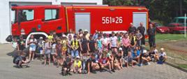 Grupa dzieci wraz ze strażakami na tle samochodu strażackiego