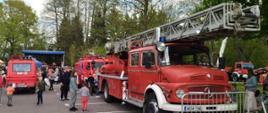 Pojazdy pożarnicze, które oglądają przybyli mieszkańcy Grodziska Mazowieckiego, w tle scena.