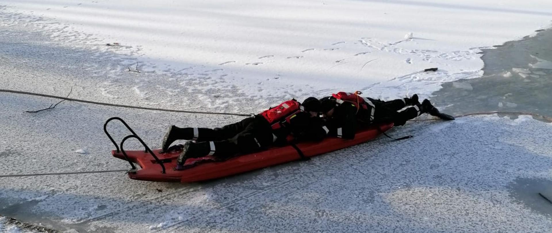 Strażacy na ćwiczeniach lodowych na lodzie z użyciem sań lodowych