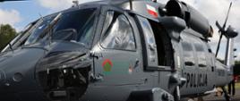 Śmigłowiec S70i Black Hawk stojący na płycie lądowiska, na drzwiach bocznych kabiny pilota śmigłowca widoczne logo Narodowego Funduszu Ochrony Środowiska i Gospodarki Wodnej oraz Państwowej Straży Pożarnej, w oddali na drzwiach bocznych śmigłowca widoczny napis Policja