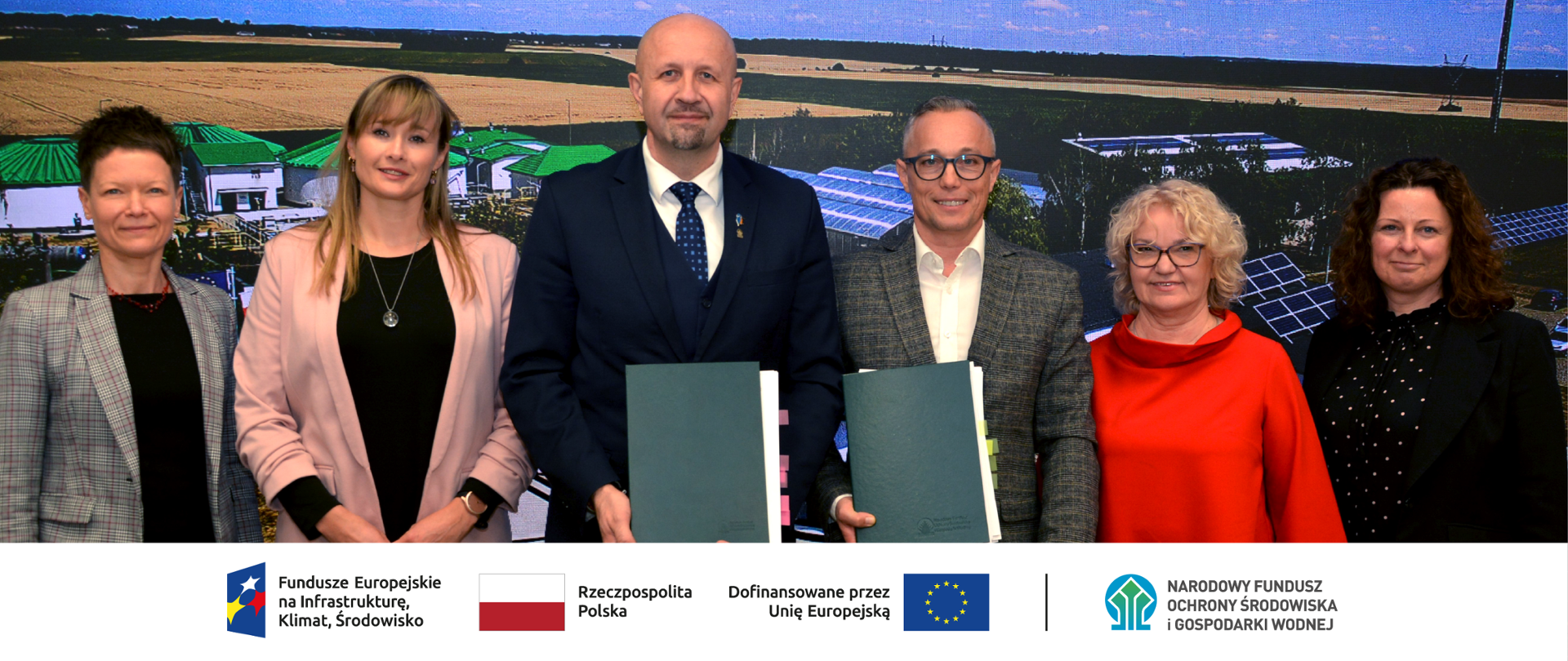 Zdjęcie grupowe. W stopce grafiki ciąg logotypów: Fundusze Europejskie na Infrastrukturę, Klimat, Środowisko, flaga Rzeczypospolita Polska, flaga UE i Dofinansowane przez UE, NFOŚiGW.