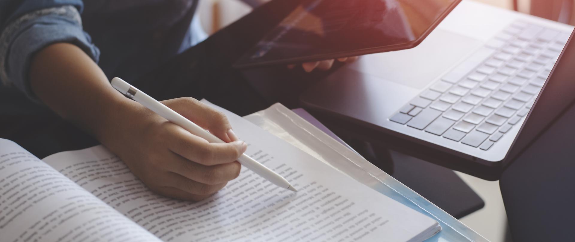 ręka z długopisem nad książką