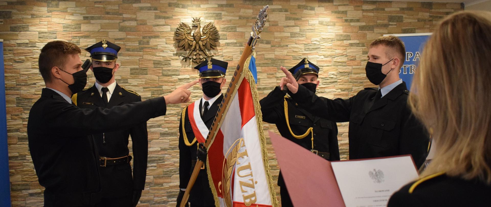 Dwóch strażaków przyjętych do służby ślubuje przy poczcie sztandarowym