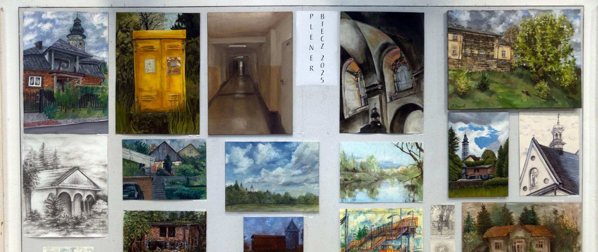 Na ścianie wiszą liczne obrazy i rysunki przedstawiające pejzaże, architekturę i wnętrza – tworzą zbiorczą ekspozycję prac z pleneru artystycznego.