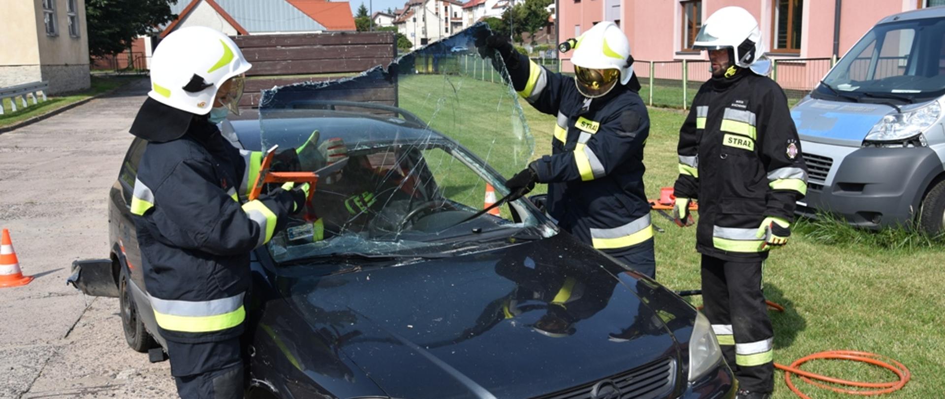 Druhowie usuwający przednią szybę samochodu osobowego